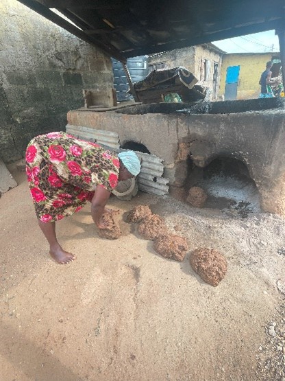 Woman fish processor in Abuesi moulding clay and repairing her fish smoking oven