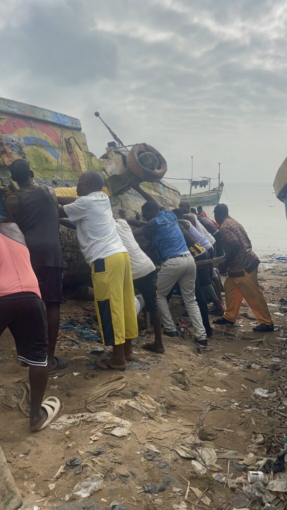 Fishermen in Abuesi seen in the process of moving a canoe into the sea