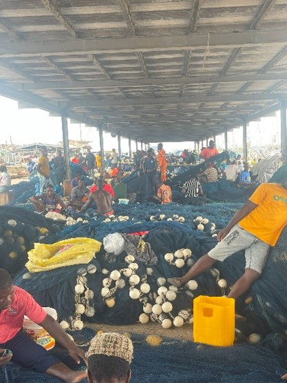 Heaps of fishing nets at a shed with fishermen working on them at the Tema canoe basin